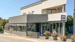 Een modern gebouw met een gevel, een bord voor een bushalte en potplanten.