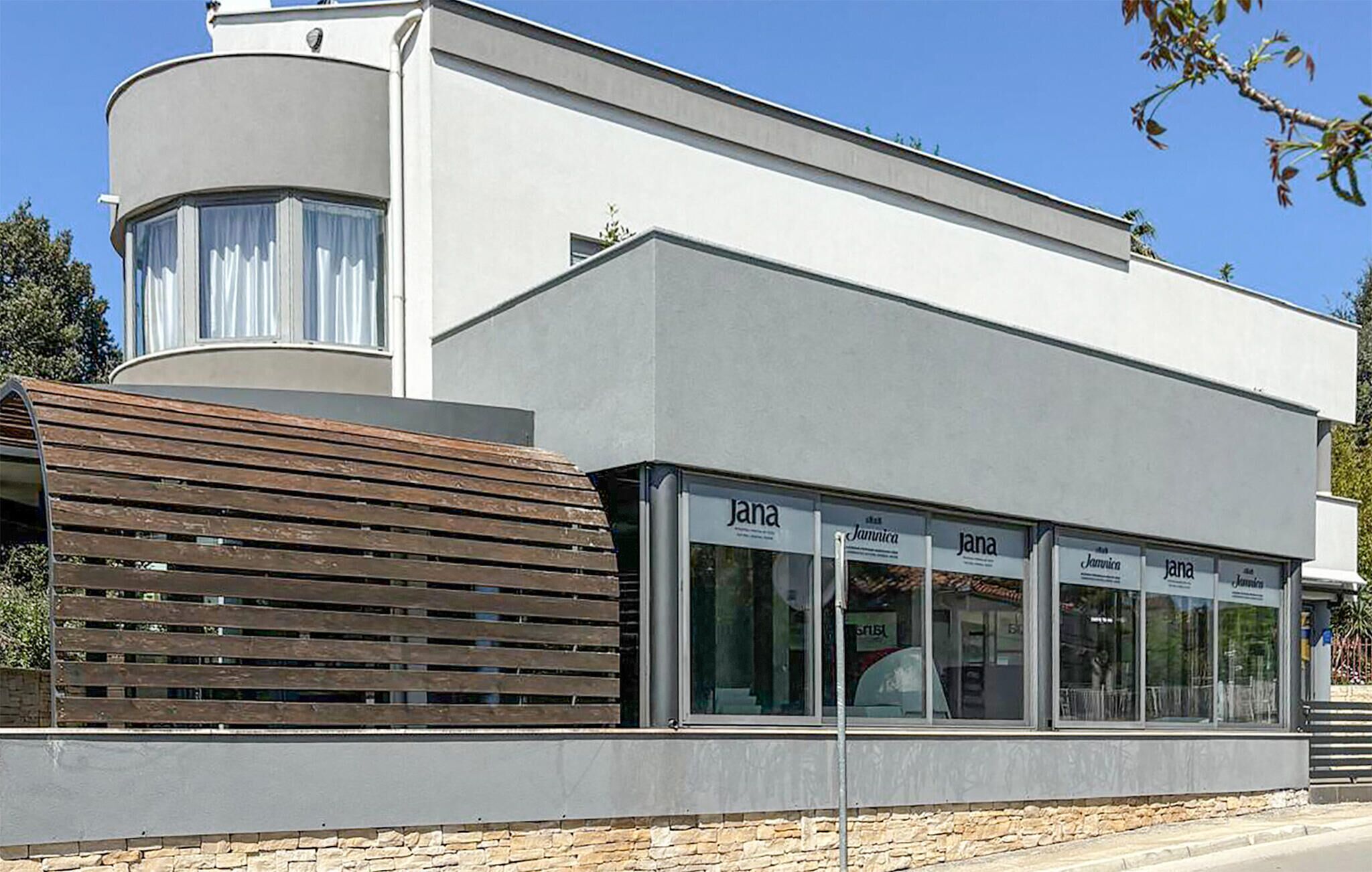 Een modern gebouw met een golvende gevel, grote ramen en een houten lamellenstructuur ervoor.