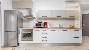 Een moderne keuken met een roestvrijstalen koelkast, een inbouwoven, een magnetron, een koffiezetapparaat en een fruitschaal.