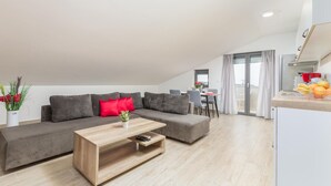 Een moderne woonkamer met een grijze bank, een houten salontafel en een eetgedeelte met een tafel en stoelen.