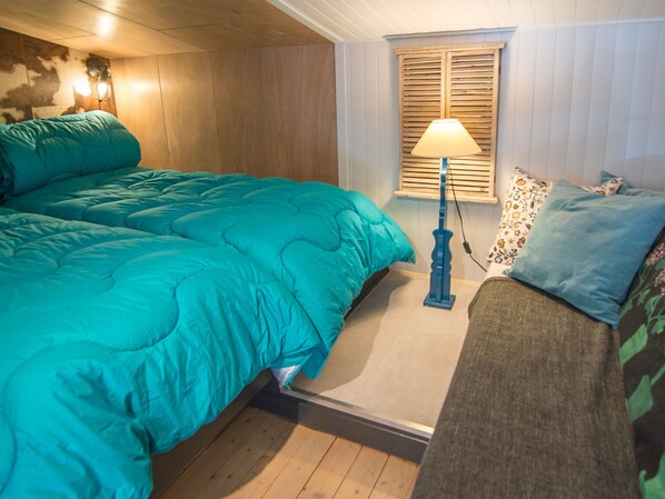 A bedroom with a large bed, a nightstand, a lamp, and a window with shutters. - Studio with wifi, Tignes, 36m², near slopes (Tignes)