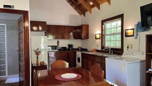 Una cocina con armarios de madera, una mesa de comedor con sillas, un refrigerador, una estufa y un fregadero.
