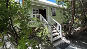 Una casa verde con una escalera blanca que lleva a una puerta.