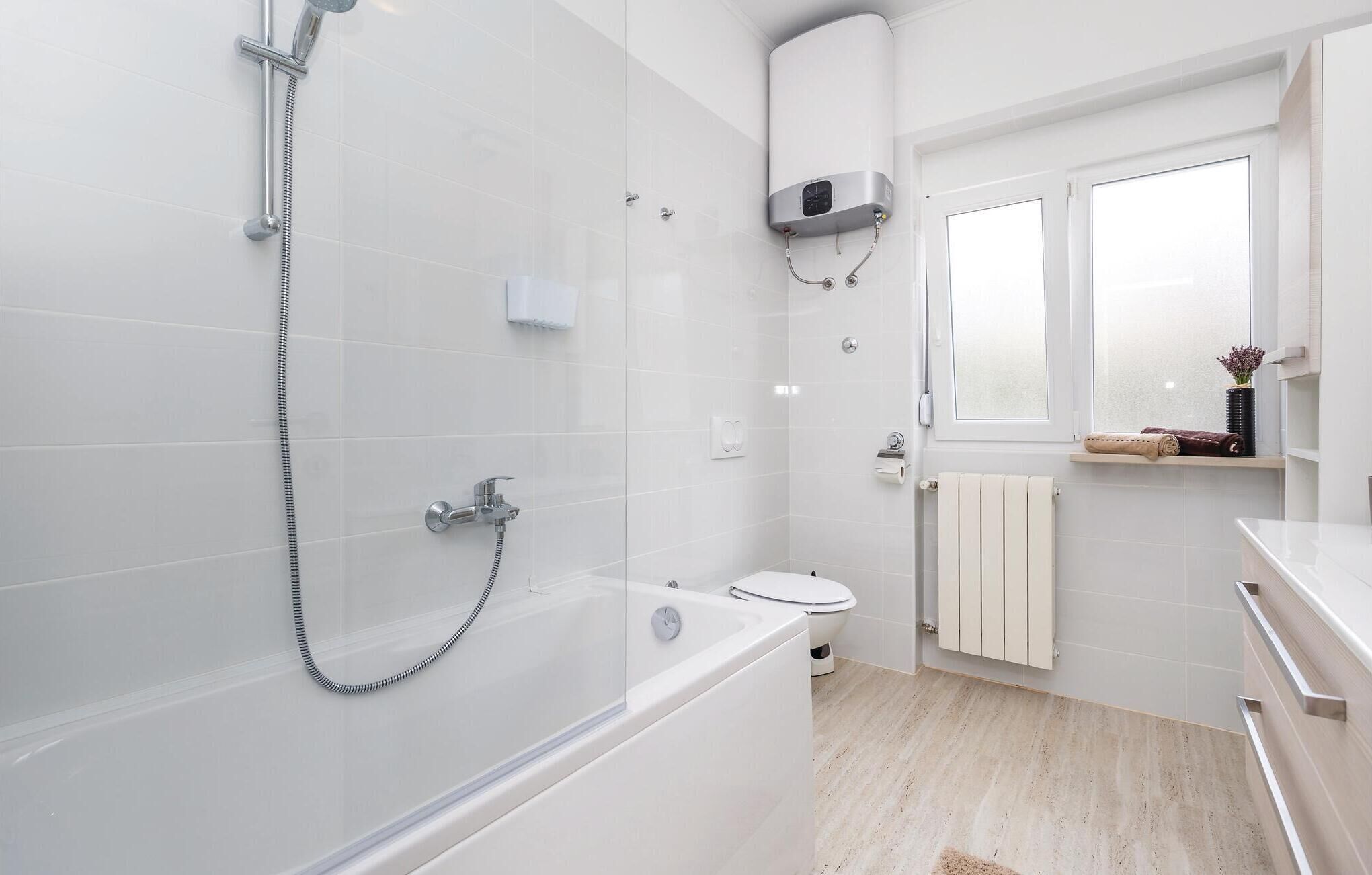 A modern bathroom with a bathtub, shower, and toilet.