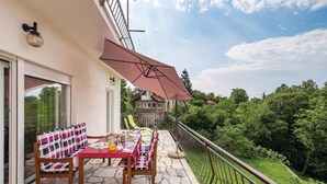 Een balkon met een tafel gedekt voor twee personen, een stoel en een grote parasol.
