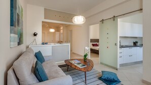 Una sala moderna con sofá, mesa de centro y vista a la cocina.