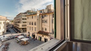 Vista desde una ventana a una calle con edificios, un café y bicicletas estacionadas.