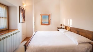 A hotel room with a large bed, a window with a view, a painting on the wall, and a nightstand with a lamp. - Awesome home in Tivat (Tivat)