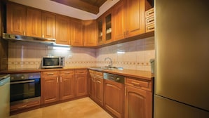 A kitchen with wooden cabinets, a microwave, a sink, and a refrigerator. - Awesome home in Tivat (Tivat)