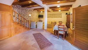 A spacious living area with a staircase, a dining table, and a TV mounted on a brick wall. - Awesome home in Tivat (Tivat)