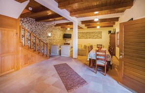 Stunning interior with a high ceiling, exposed beams, and a staircase leading to a cozy upper level with a flat-screen TV.