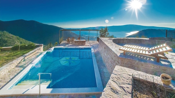 A pool with a view of the sea and mountains, a covered seating area, and a stone wall. - Awesome home in Tivat (Tivat)