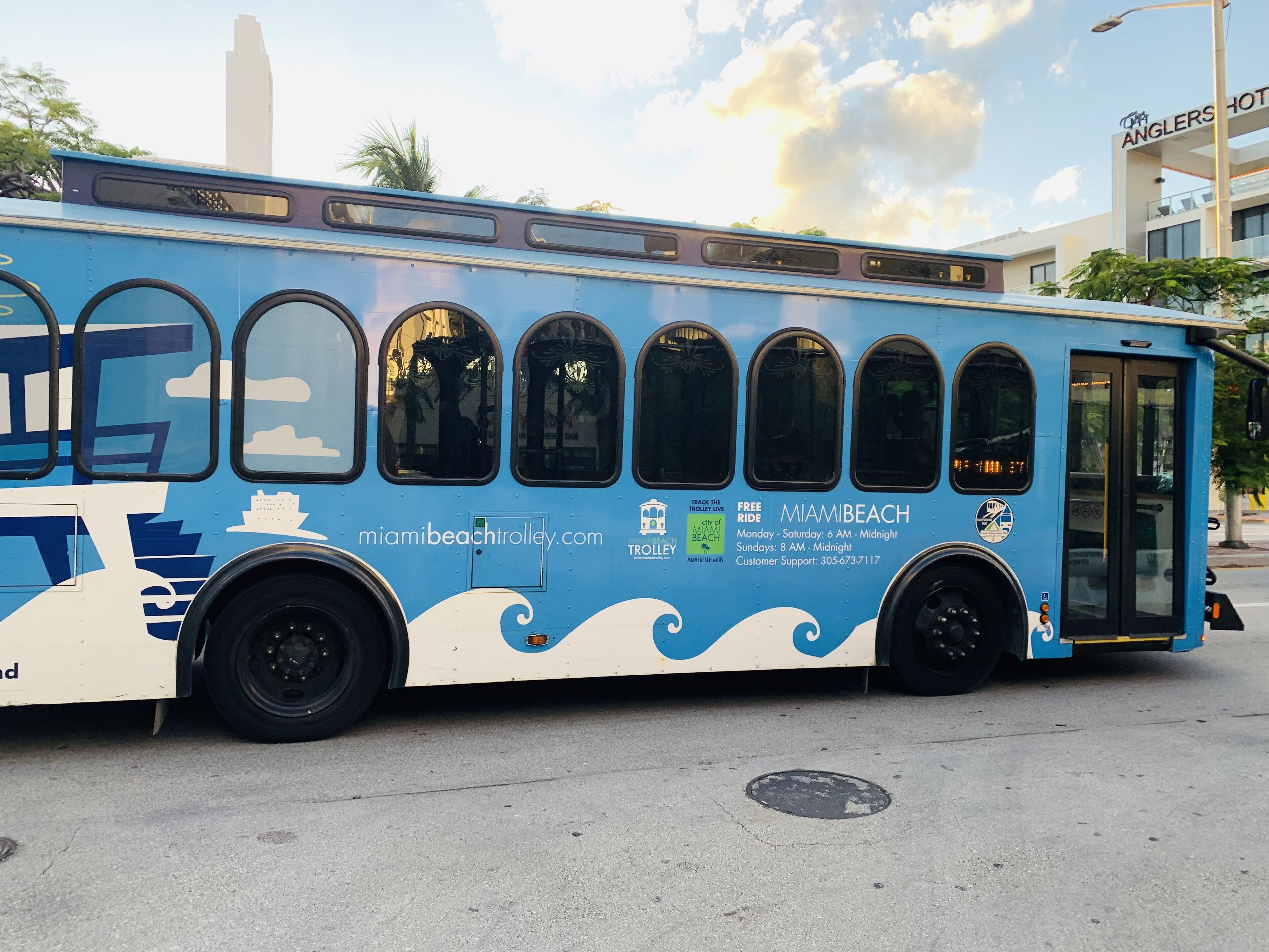 A blue bus with Miami Beach and city of Miami Beach logos, a website URL, and a customer support number.