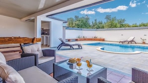 A poolside area with wicker furniture, a glass table with drinks, and a view of the pool and greenery. - Gorgeous home in Sikici (Sikici)