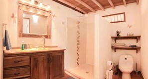 A bathroom with a wooden vanity, a large mirror, a shower area, and a toilet. - Your own personal coffee farm stay in Jardin, Colombia (Jardín)