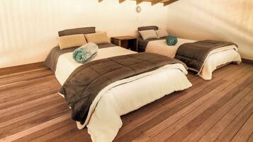A cozy bedroom with two beds, wooden flooring, and a rustic ceiling.