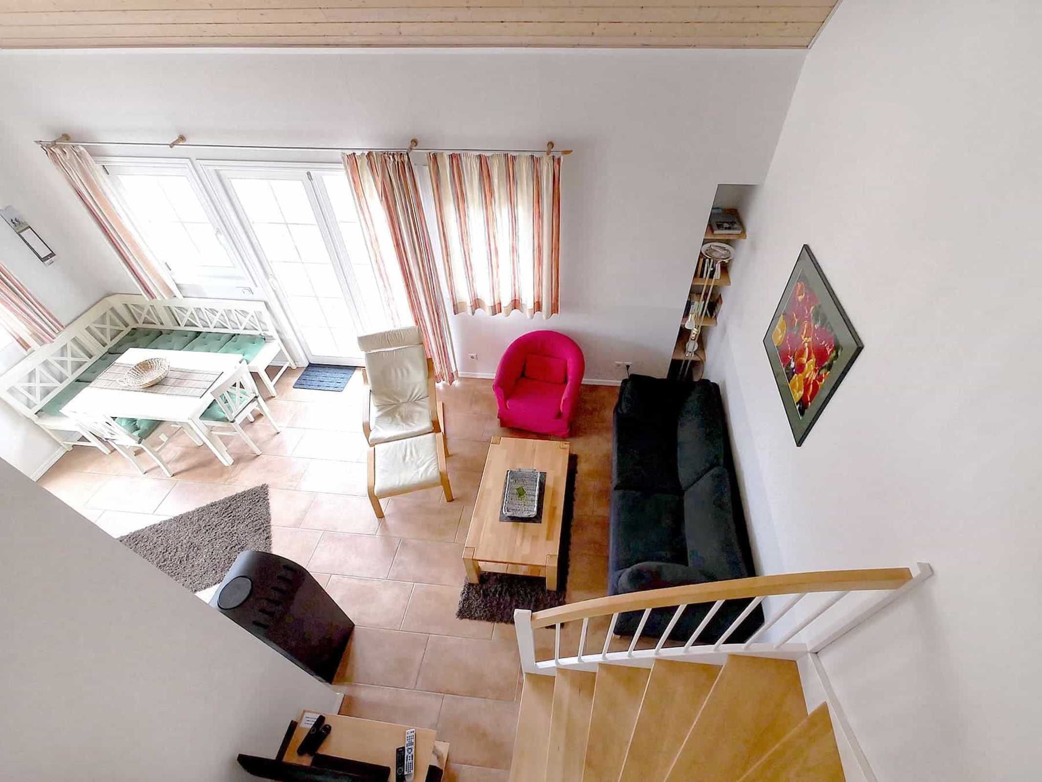 A spacious living area with a staircase, a dining area, and a bright room with curtains.