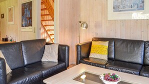 A living room with two black leather sofas, a glass coffee table with a bowl of grapes, and a wooden staircase in the background. - Amazing home in Give with sauna (Give)