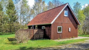 A wooden barn with a sloped roof, a small attached shed, and a wooden fence. - Amazing home in Give with sauna (Give)