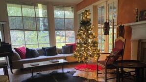Una sala de estar acogedora con un árbol de Navidad, una chimenea y un ventanal grande.