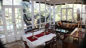 Una habitación luminosa con una mesa de comedor preparada para cuatro personas, un sofá y un ventilador de techo.