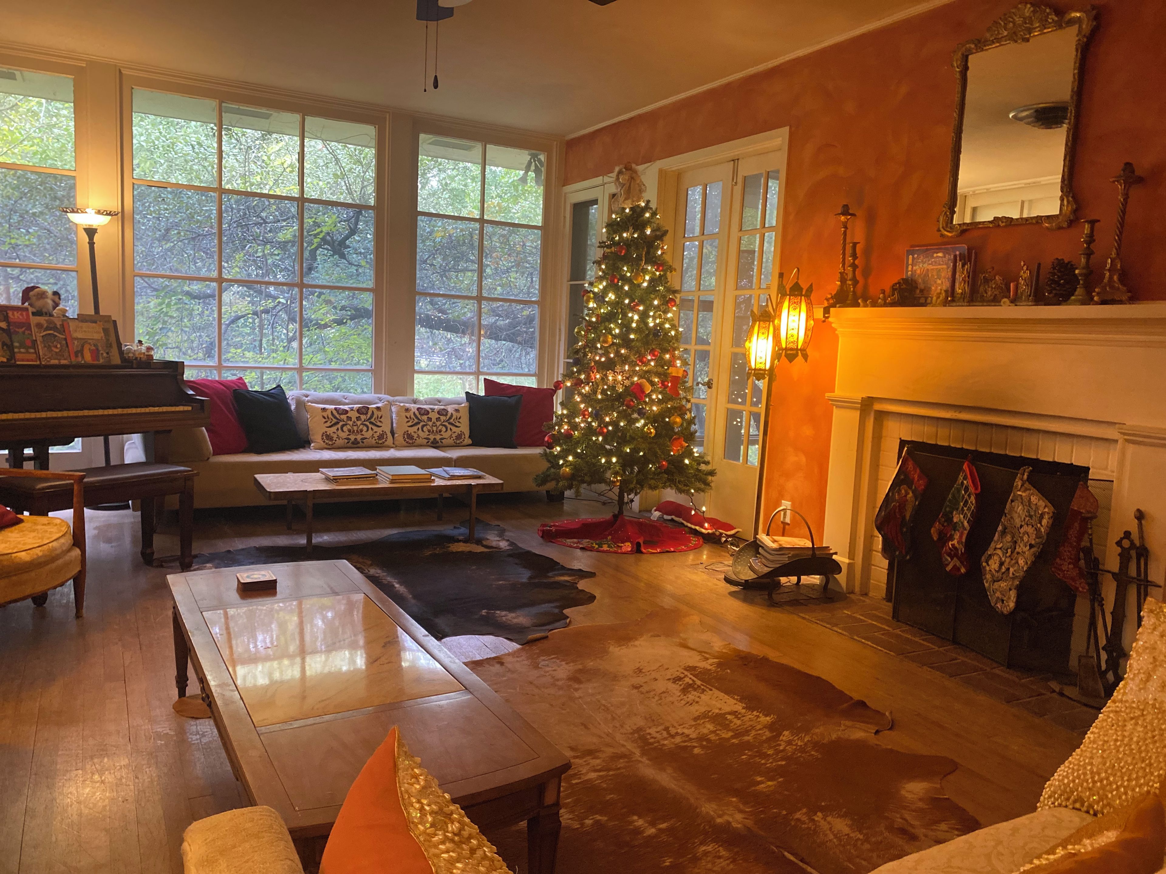 Una sala de estar acogedora con un piano, un árbol de Navidad y una chimenea.