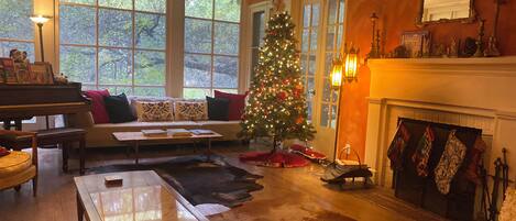Una sala de estar acogedora con un piano, un árbol de Navidad y una chimenea.