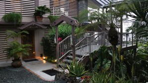 Een hotelingang met een overdekt terras, een trap en diverse planten.