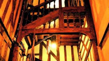 Eine hölzerne Wendeltreppe mit einer Laterne, die an der Handläufe hängt, führt auf eine erhöhte Ebene.