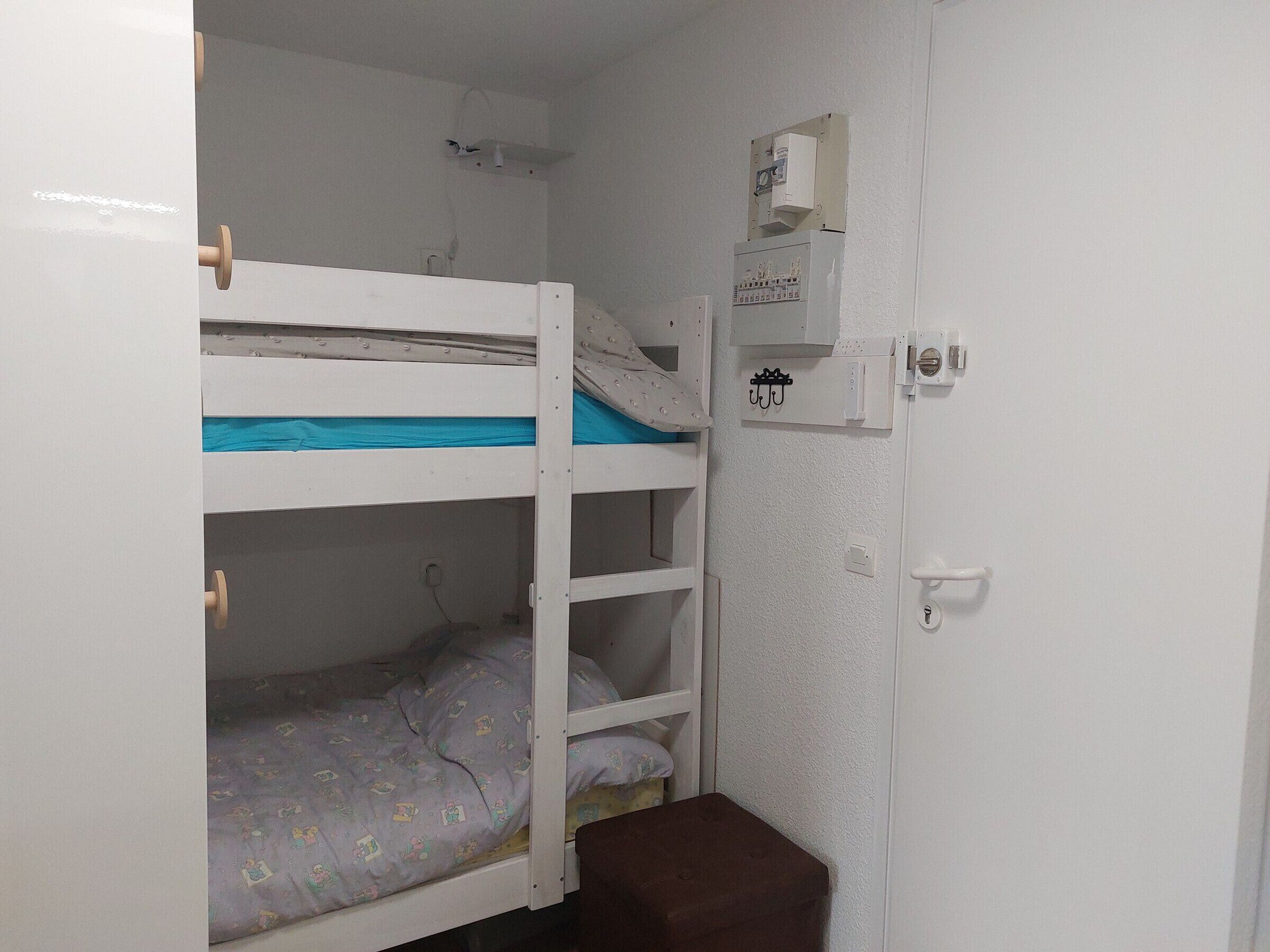 A bunk bed room with a small cabinet and a door.