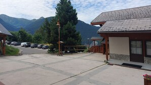 A building with a wooden facade, a parking lot with several cars, and a mountainous backdrop. - Studio in Vallandry, 4 ppl, near lifts, pets allowed (Peisey-Vallandry)