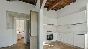 Una cocina moderna con armarios blancos, horno empotrado y piso de madera.