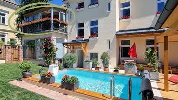 A residential property with a swimming pool, a covered patio, and a garden.