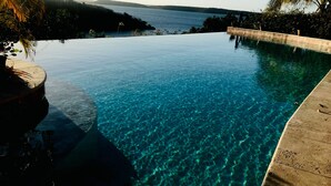 Une magnifique piscine à débordement, avec une vue dégagée sur l’étendue d’eau et les collines lointaines.
