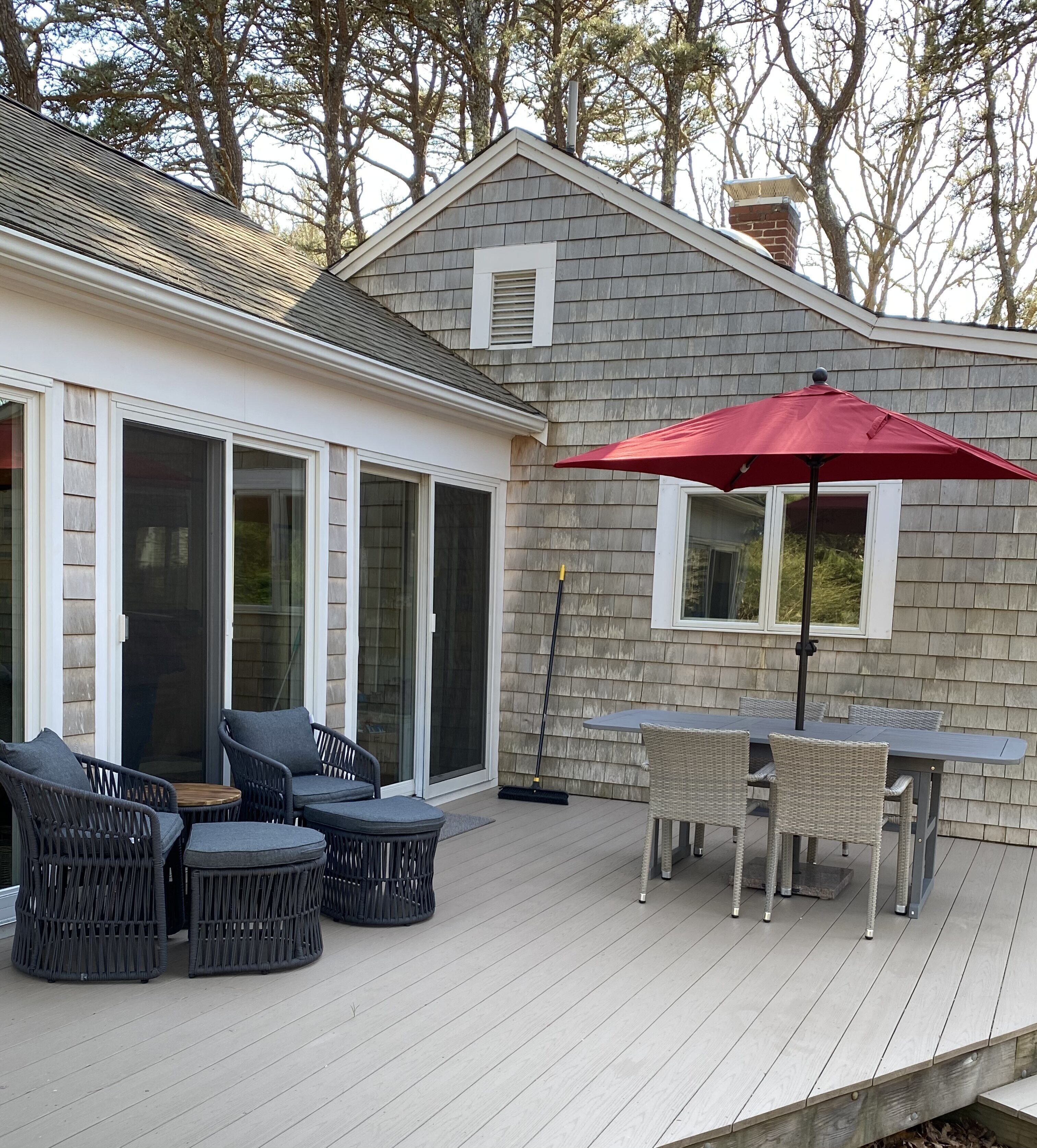 A covered patio with outdoor furniture and a red umbrella.