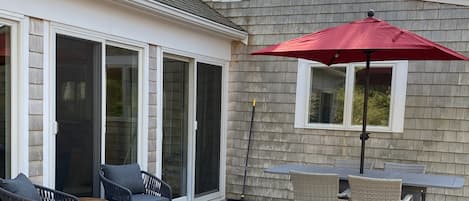 A covered patio with outdoor furniture and a red umbrella.