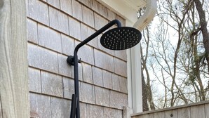 A black outdoor shower with a rain shower head, mounted on a wooden wall. - Spacious, Private Cape Cod Cottage with Central Air (Harwich Port)