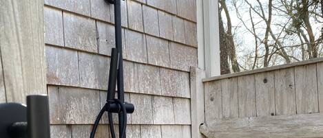 A black outdoor shower with a rain shower head, mounted on a wooden wall.
