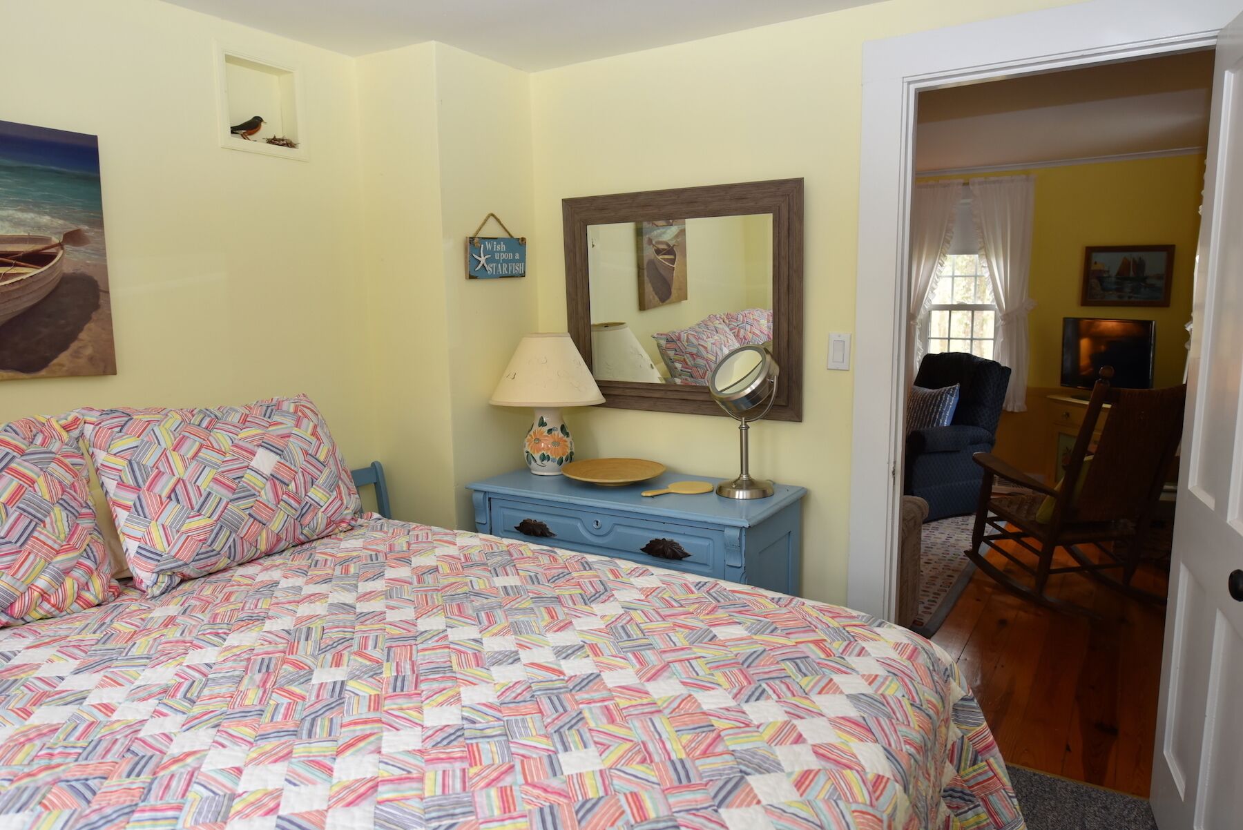 Une chambre à coucher comprenant un lit, une commode, un miroir et une porte donnant sur une autre pièce.