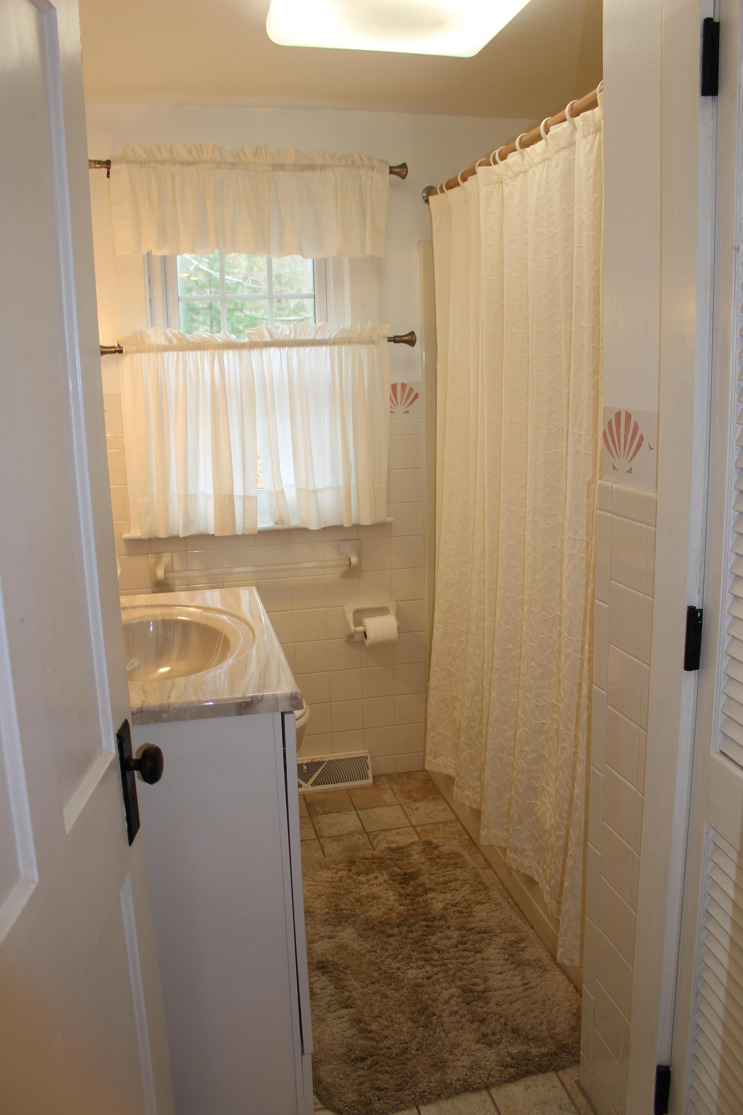 A bathroom with a sink, toilet, and shower curtain.