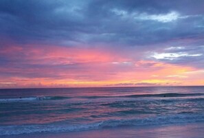 Un coucher de soleil sur l’océan, avec des vagues.