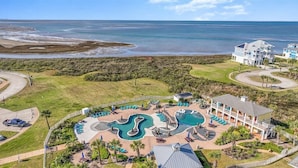 Een luchtbeeld van een resort met een groot zwembad, een strand en een ruim huis.