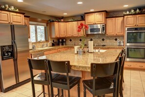 Enjoy cooking in this well-equipped kitchen with a large island, stainless steel appliances, and a window for natural light.