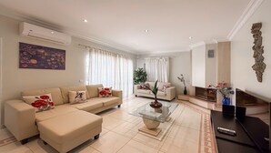 Ein modernes Wohnzimmer mit einem beigefarbenen Sofa, einem Glastisch und einem Fernsehschrank.