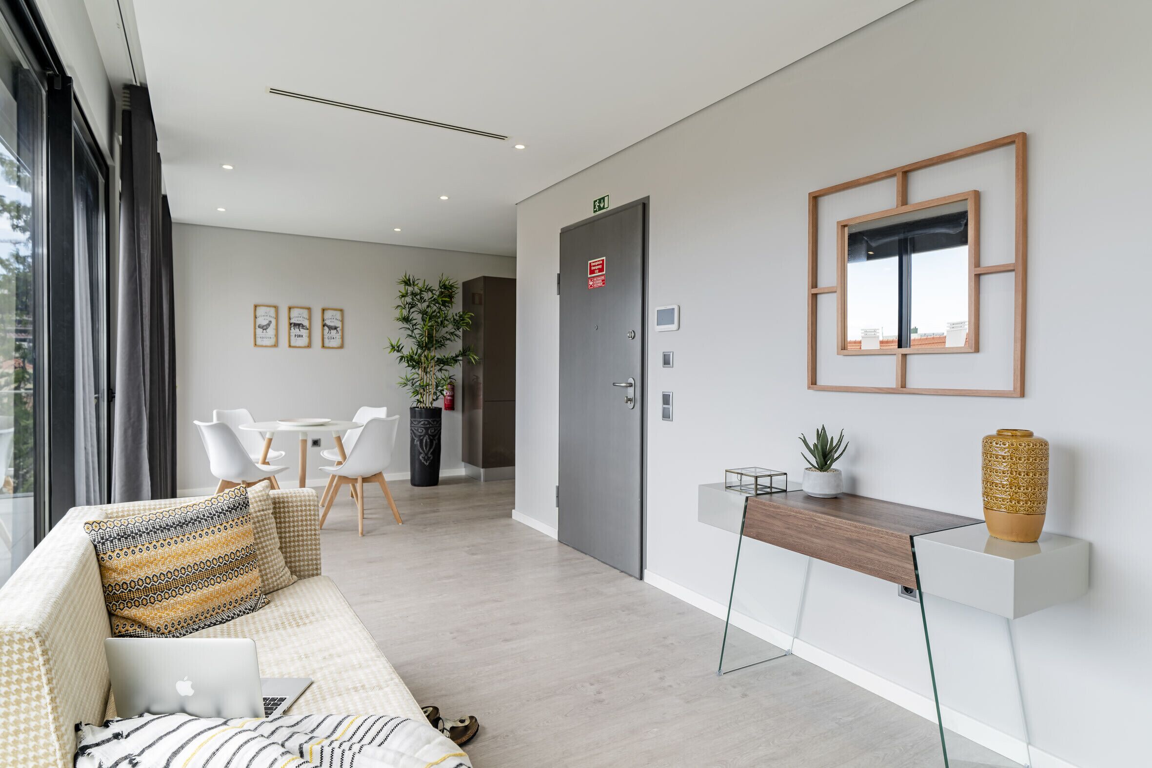 En moderne hotellobby med en sofa, et skrivebord, en plante og et indrammet billede på væggen.