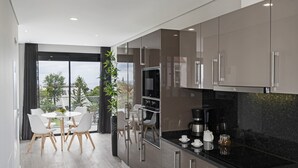 Una cocina moderna con comedor, ventanas amplias y vistas a árboles.