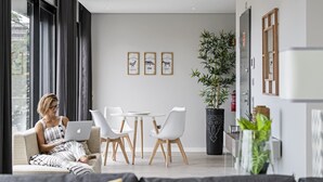 Una sala de estar moderna con un sofá, una mesa de comedor con sillas y una planta grande en maceta.