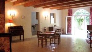 Un comedor con una mesa y sillas de madera, un piano y una araña.