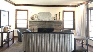Ein Wohnzimmer mit Kamin, Holzboden und einer Couch.