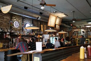 A bar with a stone wall, various liquor bottles, and hanging signs.